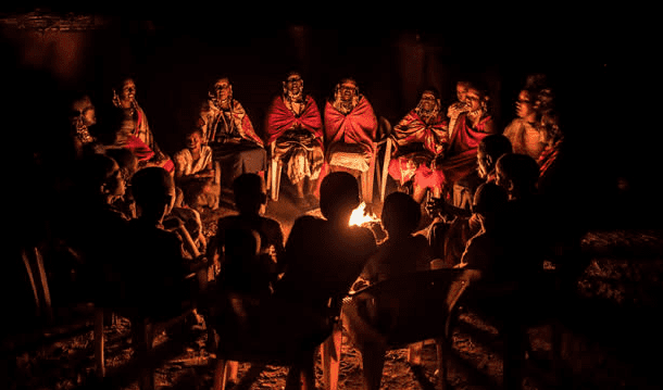 elders narrating astory around afire place
