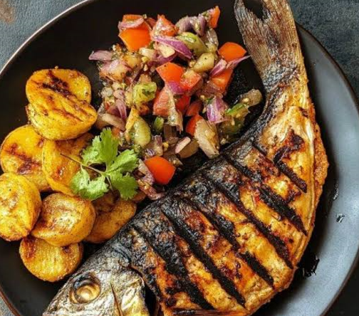 Grilling fresh Mukeke fish during Cooking Classes in Burundi