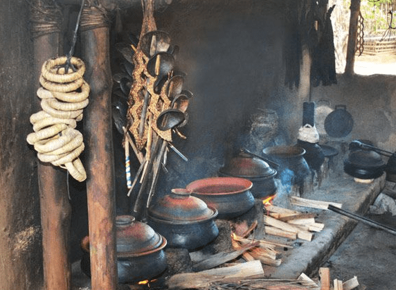A traditional Burundian kitchen setup with clay pots over an open wood fire